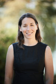A woman in a black dress smiles at the camera, embodying joy and wellness, aligning with WeNatal's focus on health and vitality.